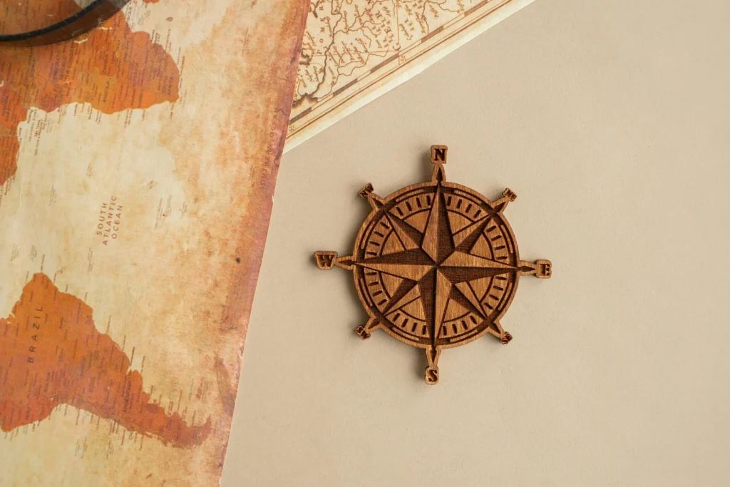 Wooden compass rose placed on a textured map background with geographical details. The Narrative Group.