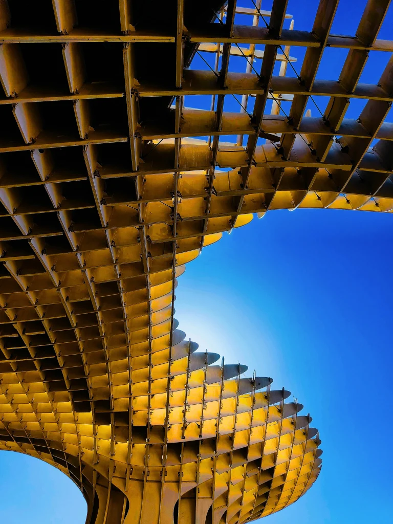 Curved architectural structure with a grid pattern against a blue sky. The Narrative Group.