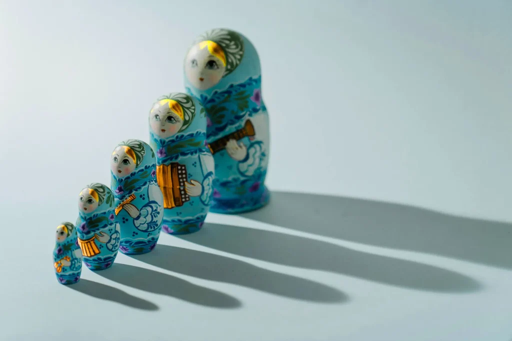 Three painted nesting dolls arranged on a white tabletop, reflecting the technology adoption life cycle for mid-market IT planning.