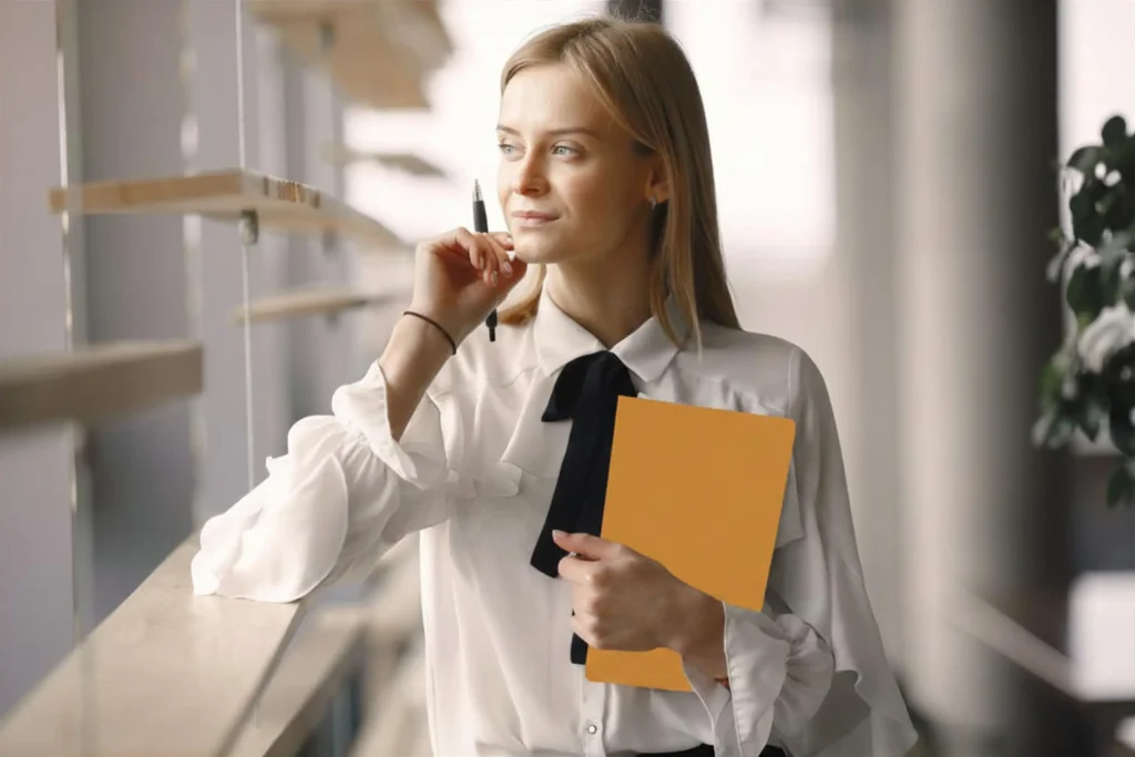 Professional woman holding a yellow folder and pen, pausing in a bright office while mapping a technology roadmap.